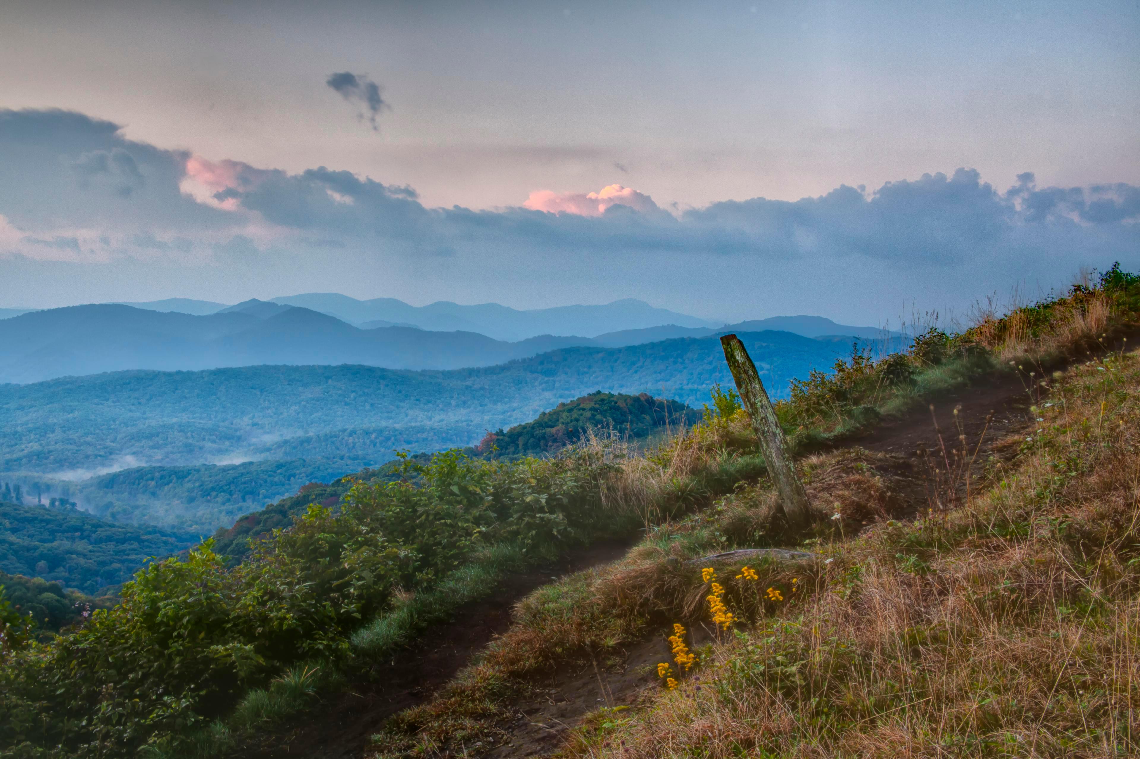 A view of rolling blue hills layered in the distance from a hiking trail in Asheville