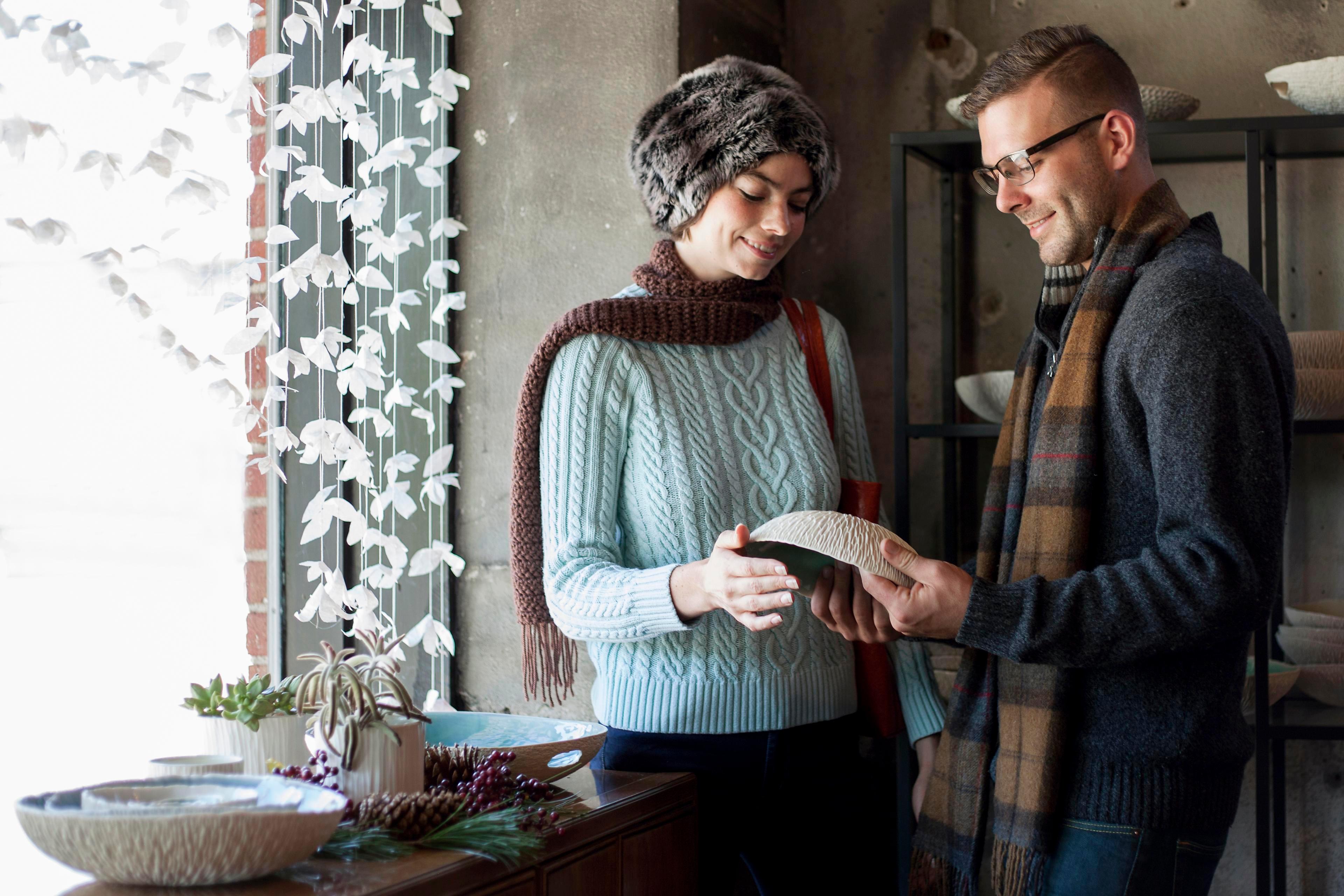 Two artists hold a ceramic bowl in Asheville