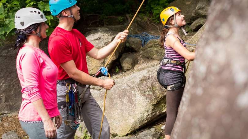 Three people prepare to climb a rock facing in Asheville, NC.