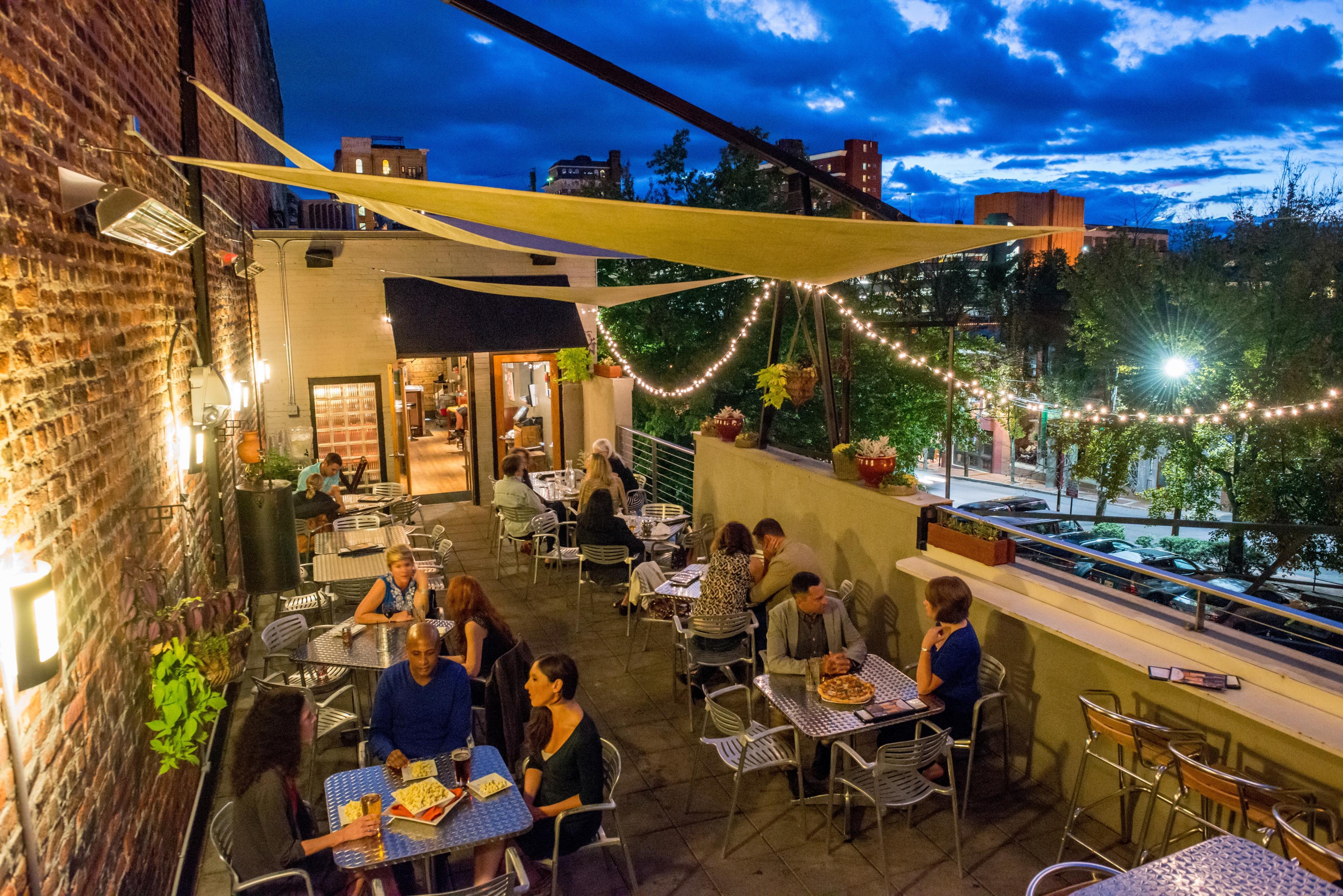 People sit at tables on an outdoor patio in Asheville