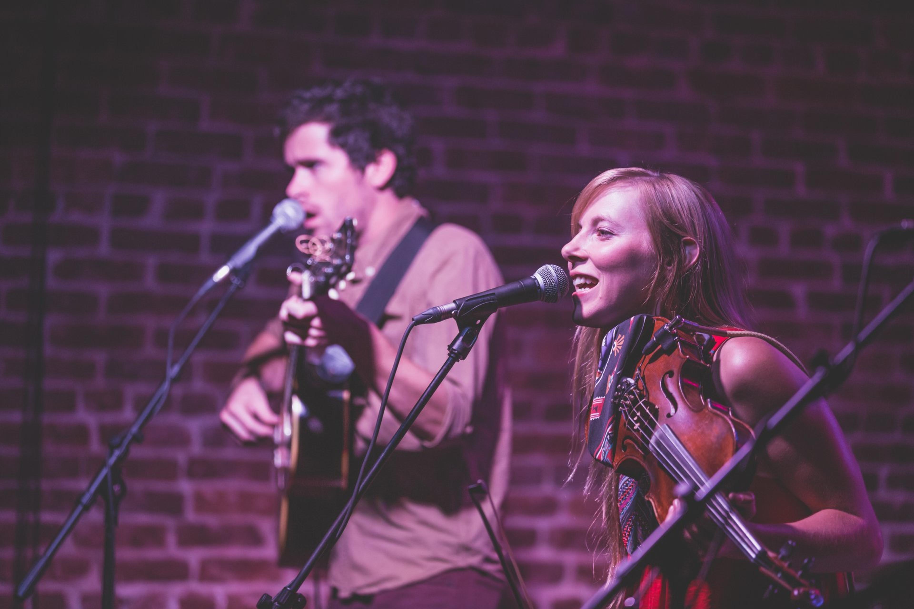 two people sing on a stage at a bluegrass concert in Asheville