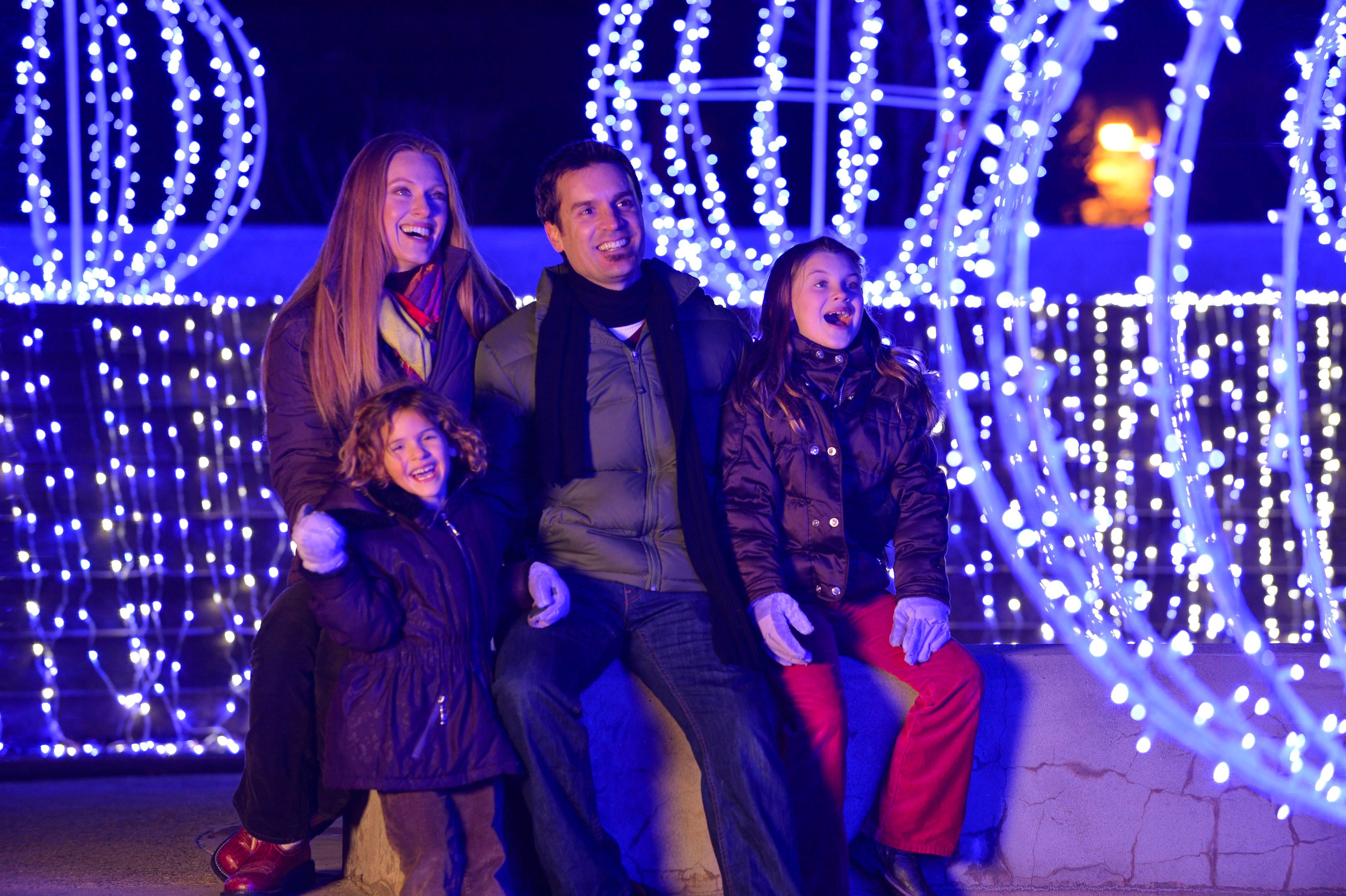 A family is surrounded by a holiday light display